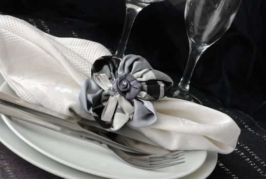 Decorative folded napkin with a clamp in the shape of a flower on a plate with cutlery