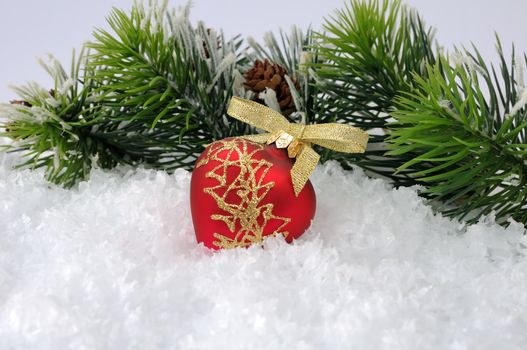 New toy in the form of a heart in the snow against the backdrop of pine branches