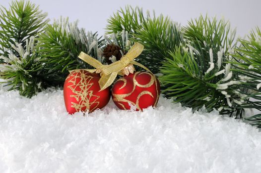 Two hearts with bows in the snow against the backdrop of pine branches