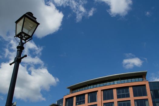 A black painted lamppost with a penthouse terrace looking out against a blue sky with cloud.