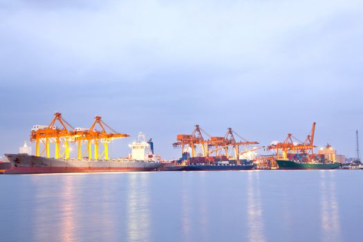 Big Container Cargo freight ship with working crane in shipyard at night for Logistic Import Export background