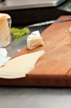 Pieces of cheese on a wooden tray.