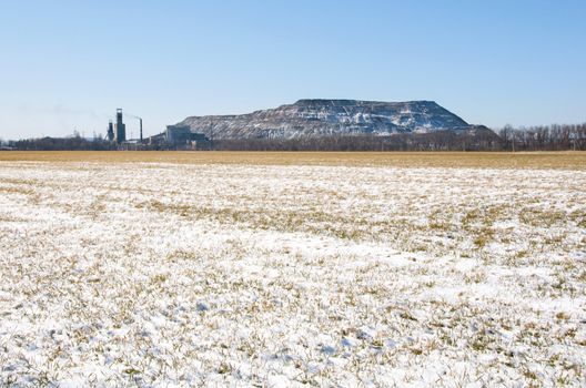 Artificial man-made rock near coal mine in Ukraine with winter field on foreground