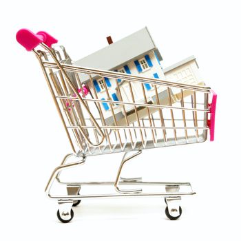 A house sits inside a shopping cart for real estate concepts.