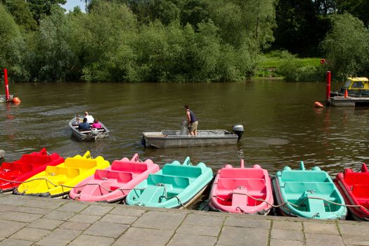 A family prepares to cruise a river in an alluminum boat with a safety person watching in another boat.