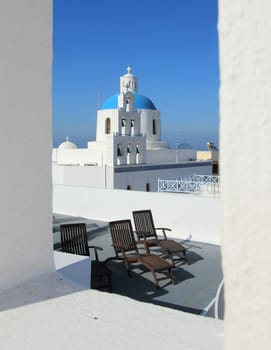 Belfry and cupola of traditional old style white Church of Panagia of Platsani viewed from a window in village Oia of Cyclades Island Santorini Greece on the blue sky background