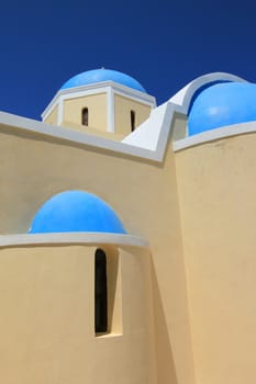 Close up of blue dome and yellow walls of a greek orthodox church in Santorini island, Greece, by beautiful weather