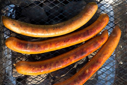 Four done sausages on a hot grill