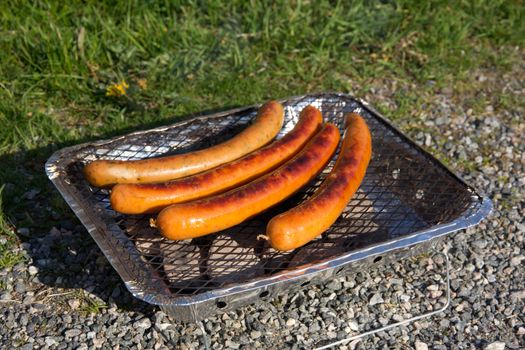 Four done sausages on a hot grill
