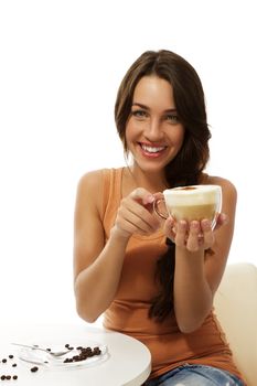 happy young woman with a cappuccino coffee sitting at a table on white background