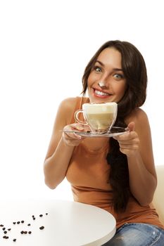 young woman with cappuccino coffee has milk foam on her nose on white background