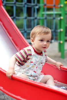 Cute little boy  come down from the children`s slide. Summer