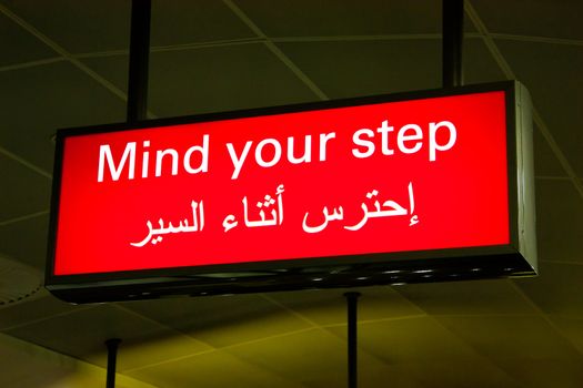 Mind your step sign in an international airport in Middle East with Arabic information