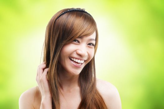 Cheerful Asian female combing her hair using finger