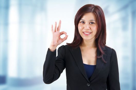 Mixed race Mid Adult Asian showing ok hand sign in work place