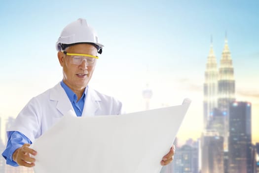 Senior Asian engineer with blueprints standing outside modern building