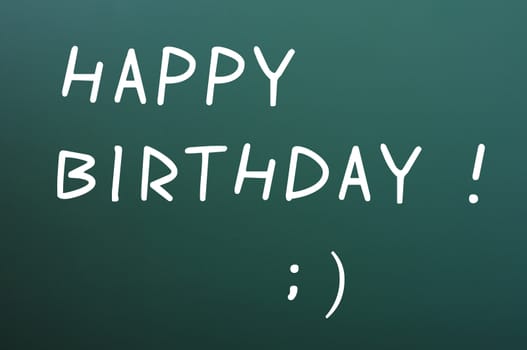 Happy birthday written with white chalk on a blackboard