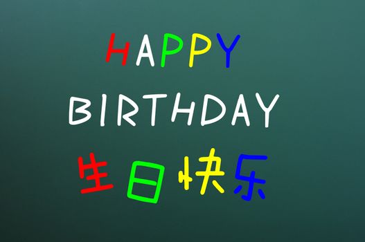 Happy birthday written with colorful chalk letters on a blackboard,with Chinese characters