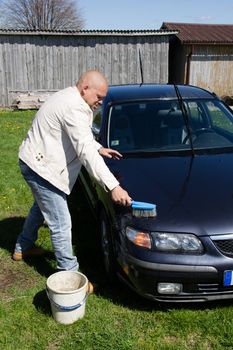 Man washing car in a countryside outdoors