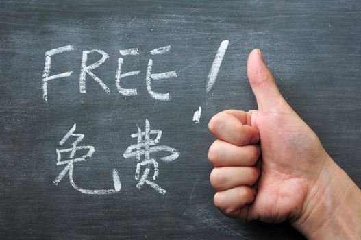 Free - word written on a smudged blackboard with a Chinese translation, with a thumb up gesture