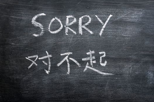 Sorry - word written on a smudged blackboard with a Chinese translation