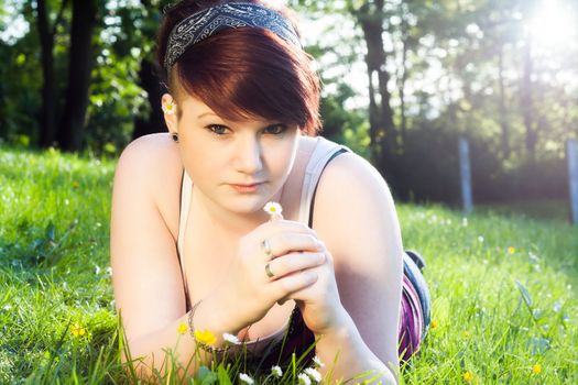 A beautiful young girl lying on the grass on a background of green