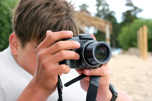 teenager with digital photo camera aiming outdoor