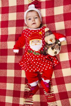 View of a newborn baby on a Christmas suit with stuffed toy.