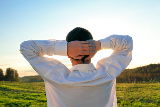 young man in the summer field contemplate the sunset