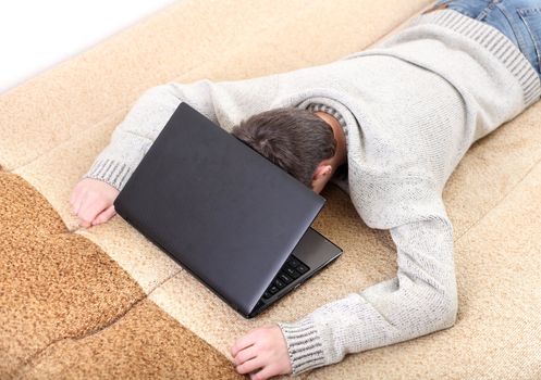 tired young man falling asleep with notebook on sofa