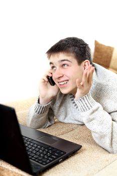 happy teenager with notebook talking on mobile phone in home interior