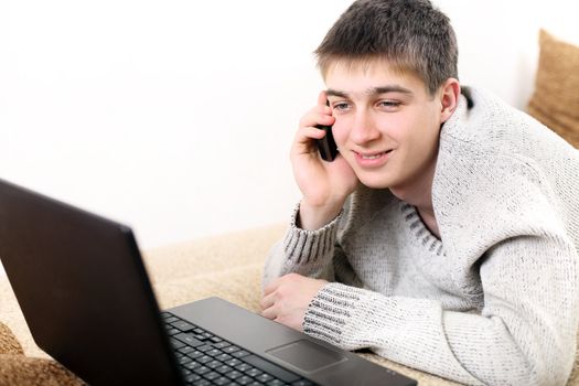 happy teenager with notebook talking on mobile phone in home interior