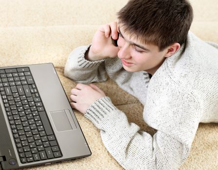 happy teenager with notebook talking on mobile phone in home interior