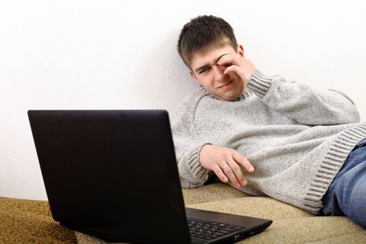 tired young man with notebook on sofa