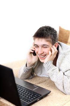 happy teenager with notebook talking on mobile phone in home interior