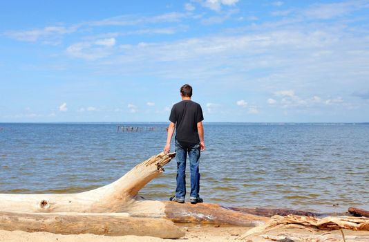 young man at seaside looking on the sea in the summer sunny day