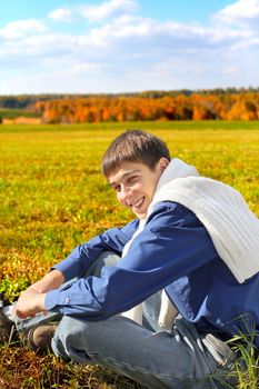 young man sitting in the autumn field