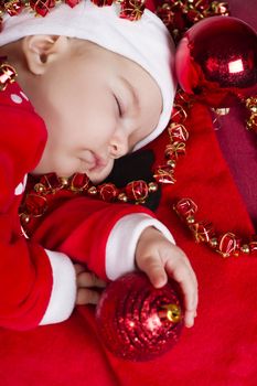 View of a newborn baby on a Christmas suit sleeping.