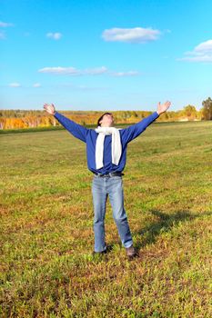 man on autumn field rising up his hands