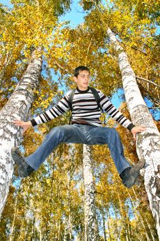 happy teenager climbing on the tree in the autumn forest