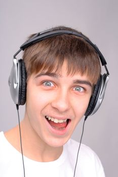 amazed teenager in the headphones on the gray background