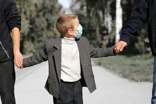 kid in the flu mask on the street with two persons