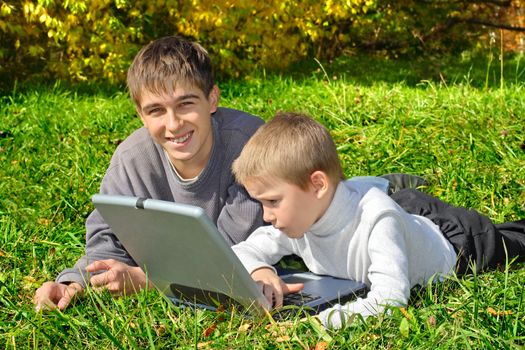 teenager and kid with notebook on the meadow