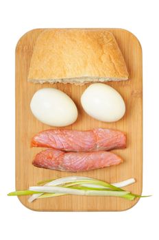 Light breakfast. Eggs, salted salmon, muffin and onion on a wooden board. Isolated on white.