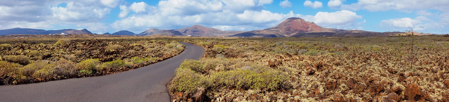 Panorama of empty road crossing the lava in the mountain, Lanzarote, Canary islands, Spain. Vertical view