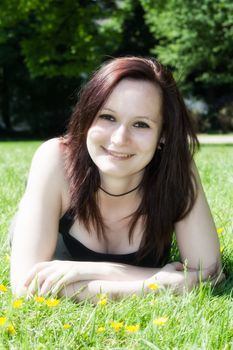 A beautiful young girl lying on the grass on a background of green