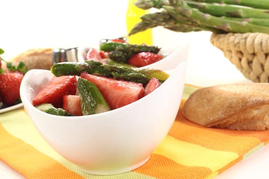 fresh Asparagus salad with fresh strawberries, oil, and bread on a light background