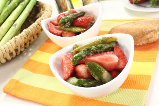 fresh Asparagus salad with strawberries and bread on a bright background