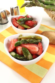 Asparagus salad with strawberries and bread on a light background