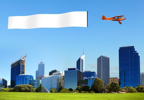 Plane in the sky above the city with blank flag